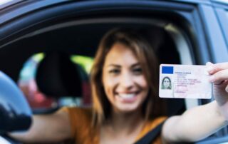 Bild: sitzende Frau im Auto hält Führerscheinkarte aus dem Fenster