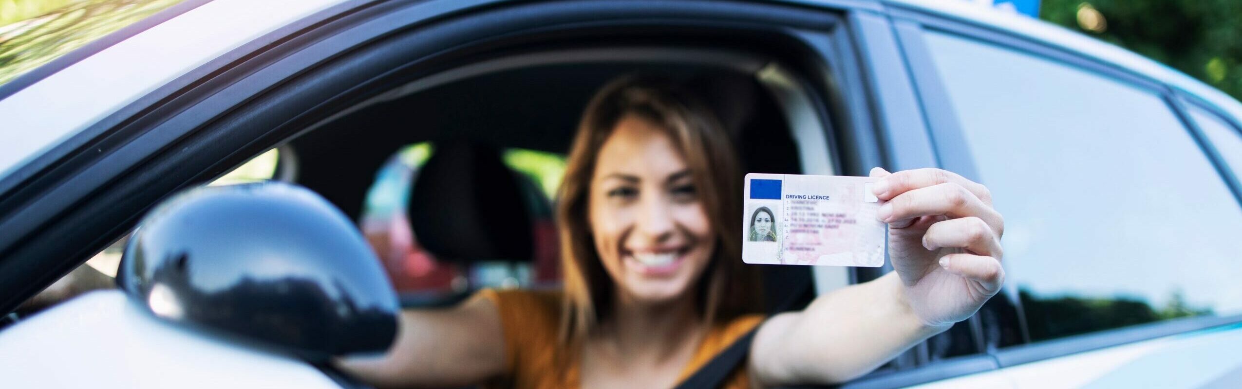 Bild: sitzende Frau im Auto hält Führerscheinkarte aus dem Fenster