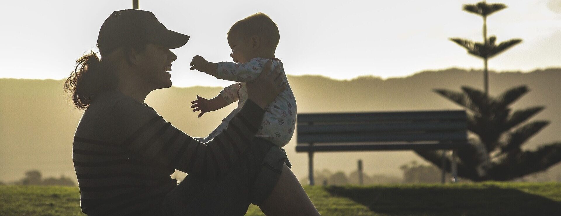Titelbild zur Seite: Frau (sitzend) mit Schirmmütze und Baby auf den Knien