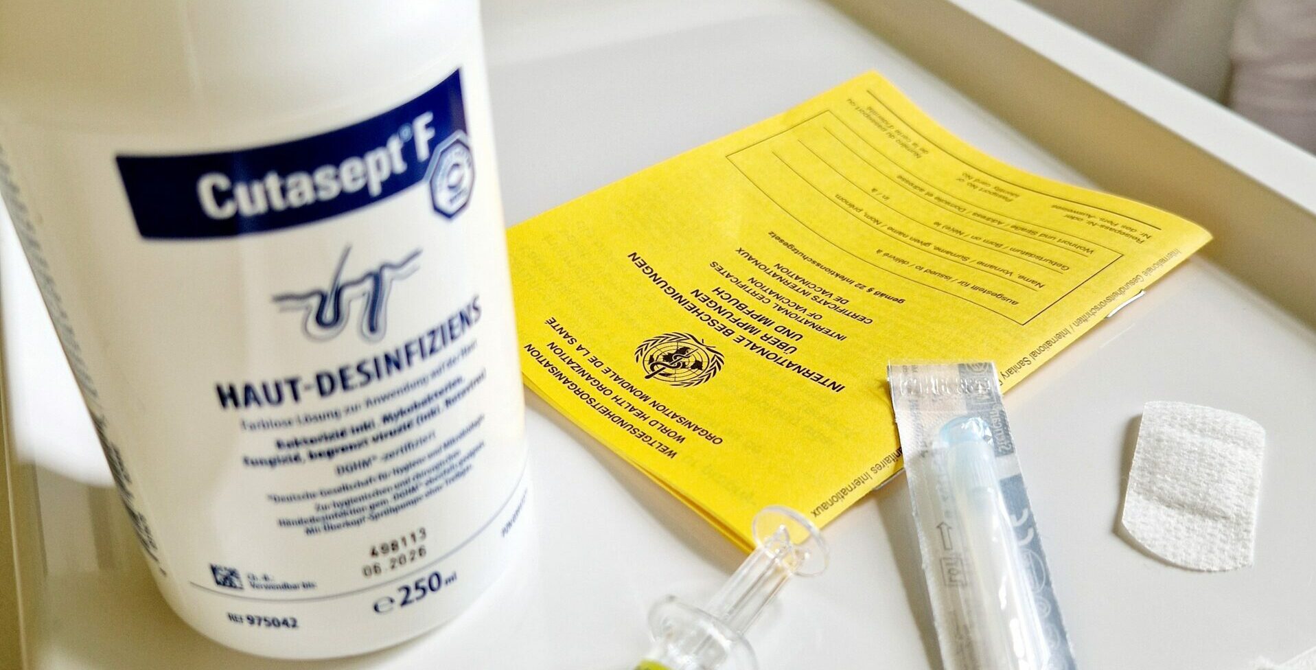 Impfung & Beratung gelbes Impfbuch, Desinfektionsmittel und Spritze