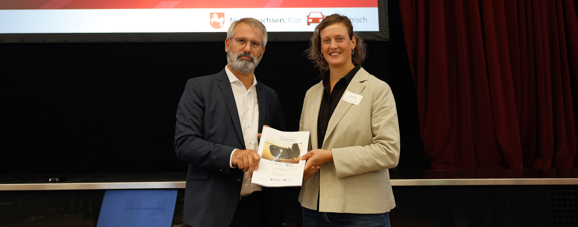 Timo Quander übergibt Larissa Jaegerdas Ladeinfrastrukturkonzept.